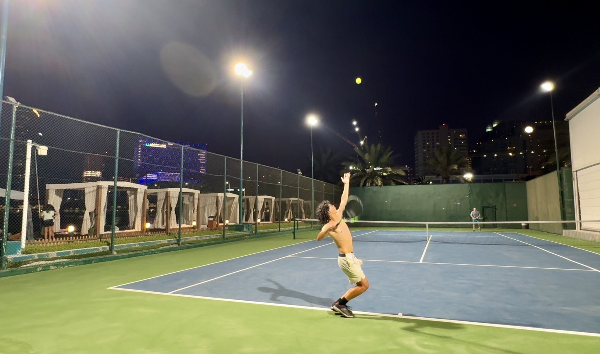 Michael Brown serving on a tennis court at night